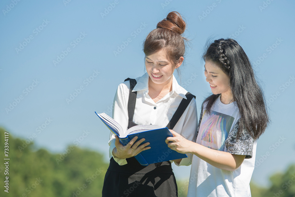 两名年轻学生在学校公园看书