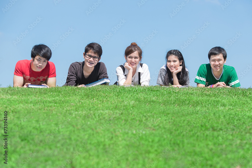 Group of students outdoors lying on the floor and smiling