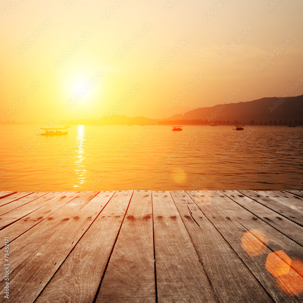 plank board with lake in sunset as background