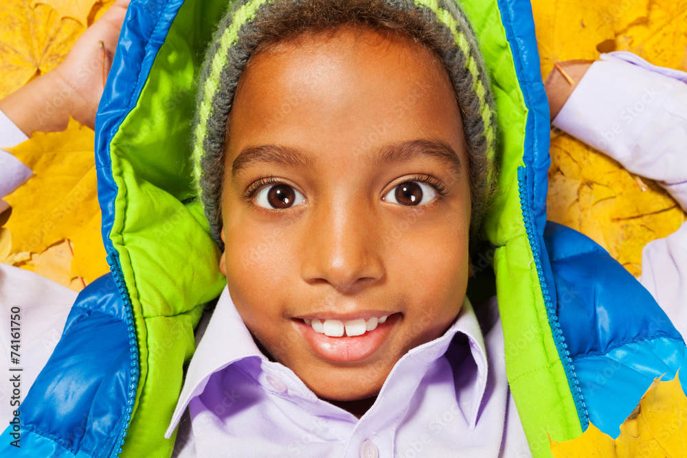 Close portrait of black boy in autumn leaves