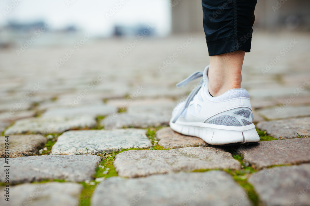 女性慢跑者在人行道上行走的腿