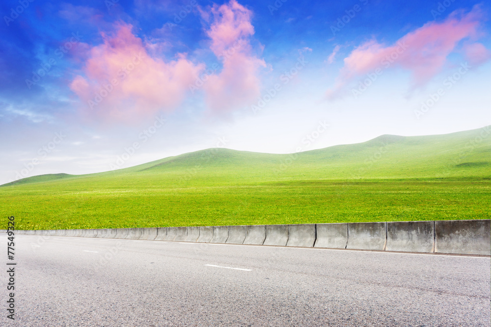 穿过草地的道路，背景是云朵和天空