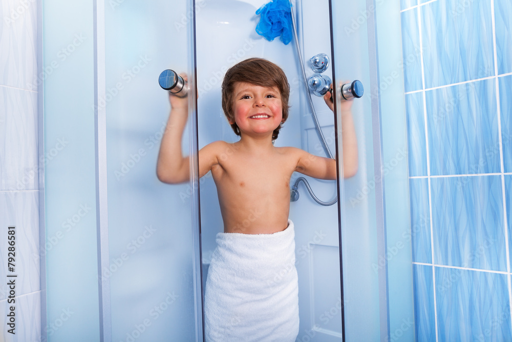 Happy little boy getting out of shower cabin