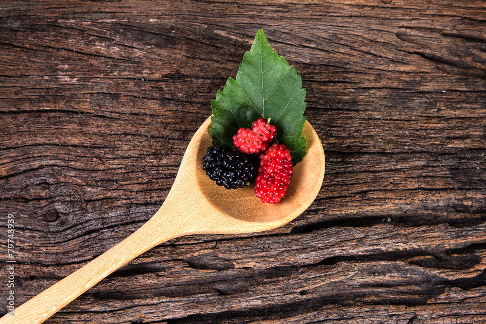 mulberry fruit in the wooden spoon on wood plate