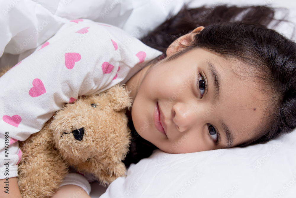 Adorable little Asian girl sleep on her bed with bear doll