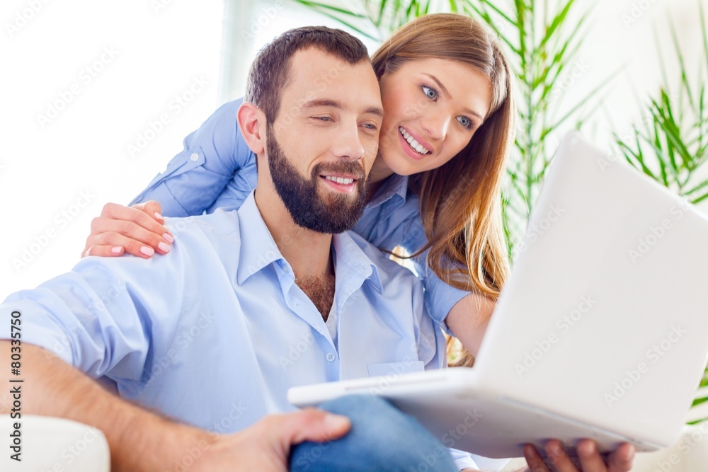 Net. Surfing web is fun. Cheerful young couple working on laptop