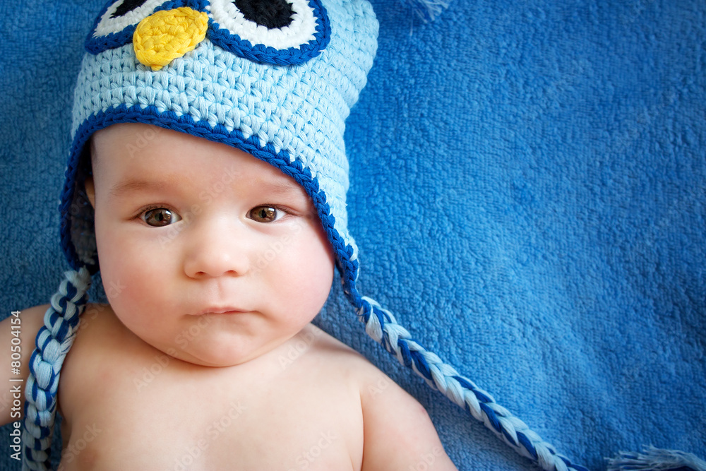 small baby in owl hat on blue background