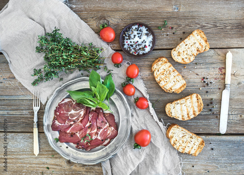 Smoked meat in vintage silver plate with fresh basil