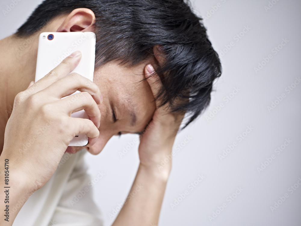 young man talking on cellphone looking sad and depressed