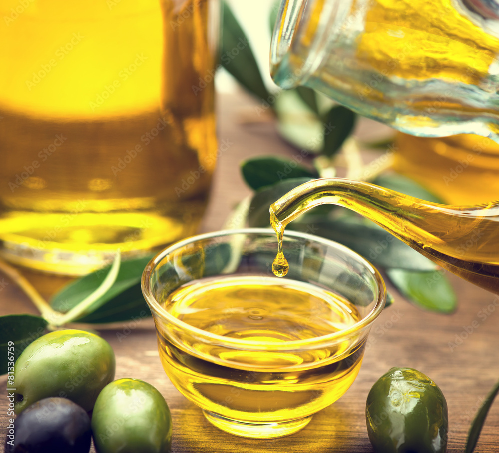 Olive oil. Bottle pouring virgin olive oil in a bowl closeup