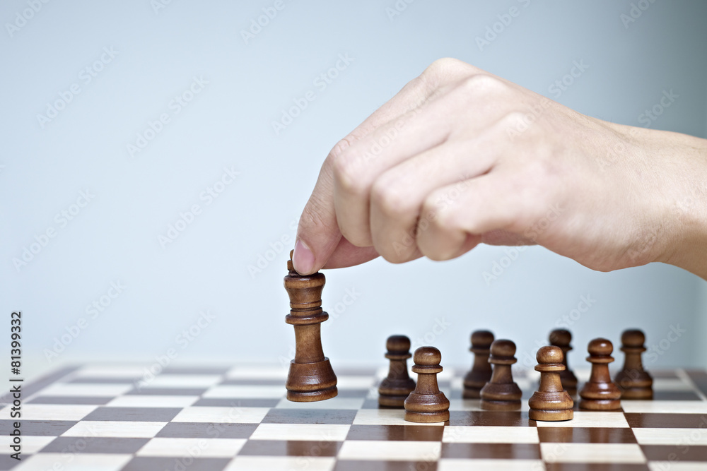 close-up of a mans hand moving a chess piece