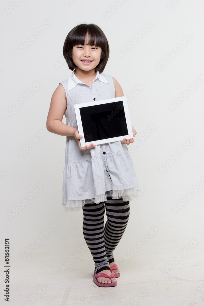 Little asian girl smiling and holding tablet computer on isolated background