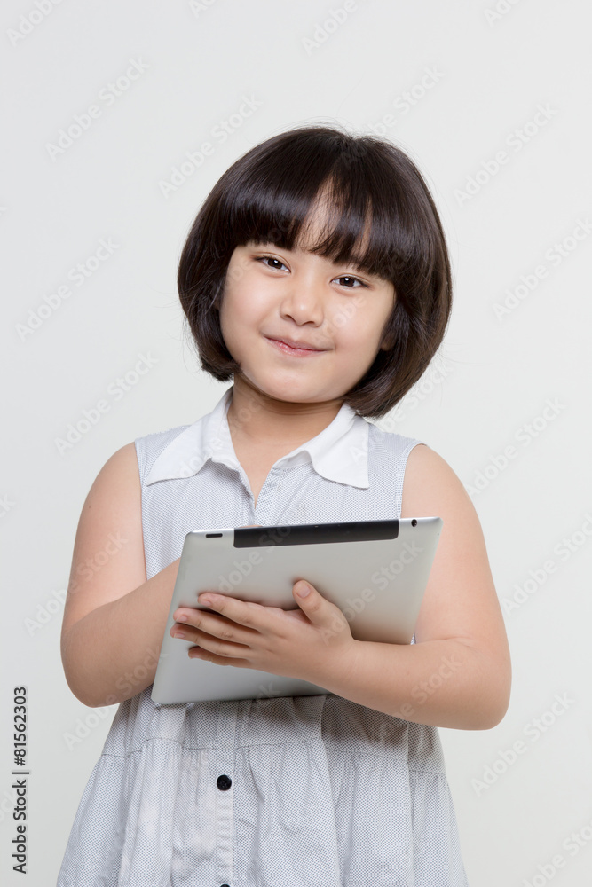 Little asian girl smiling and holding tablet computer