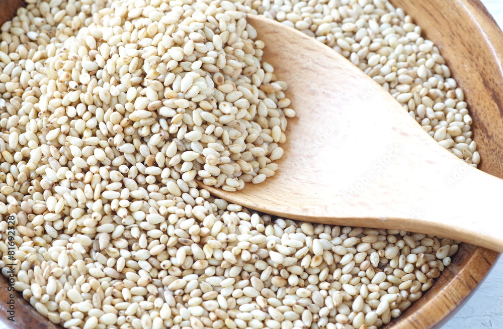 Organic natural sesame seeds on white wood table.