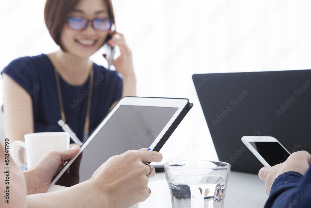 Four people are using electronic devices during a meeting