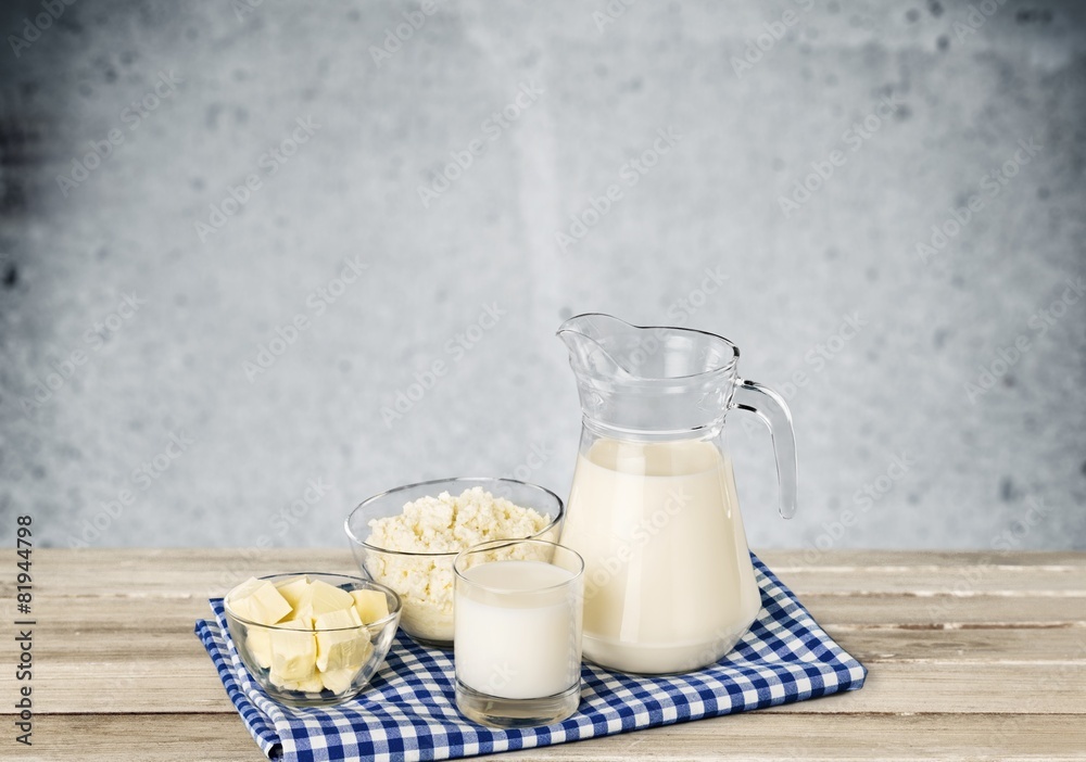 Milk. A glass of milk and a milk jug on plaid tablecloth.