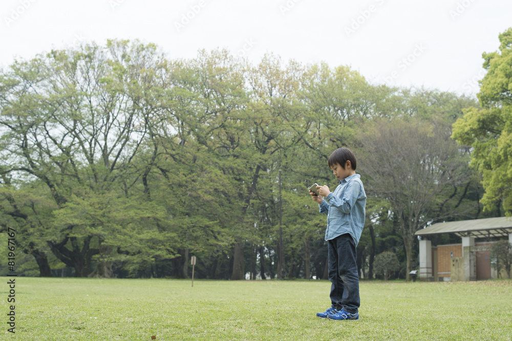 草坪公园里痴迷手机游戏的男孩