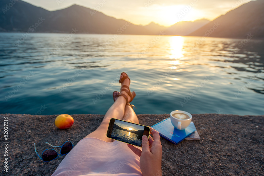 Woman holding phone lying on the pier