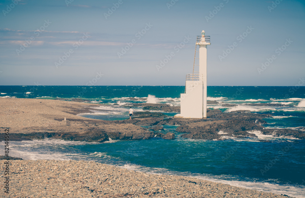 Lighthouse on the beach against blue sky