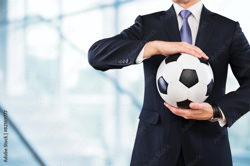 Soccer. Elegant businessman holding a soccer ball, close up