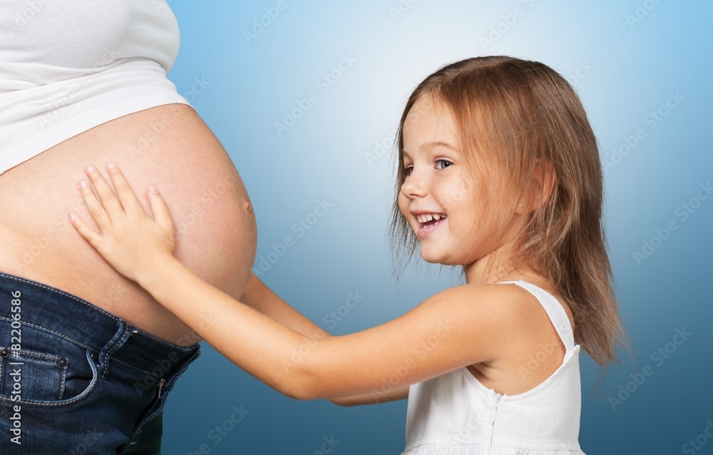 Green. Happy child holding belly of pregnant woman against green