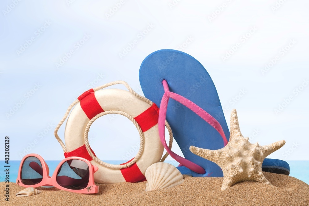 Beach. Flip-flops and sunglasses on sand beach.