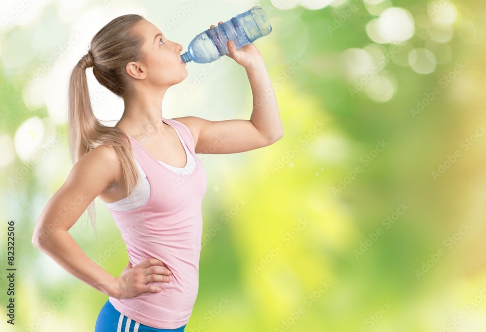 Women. Fitness woman drinking water after running at beach