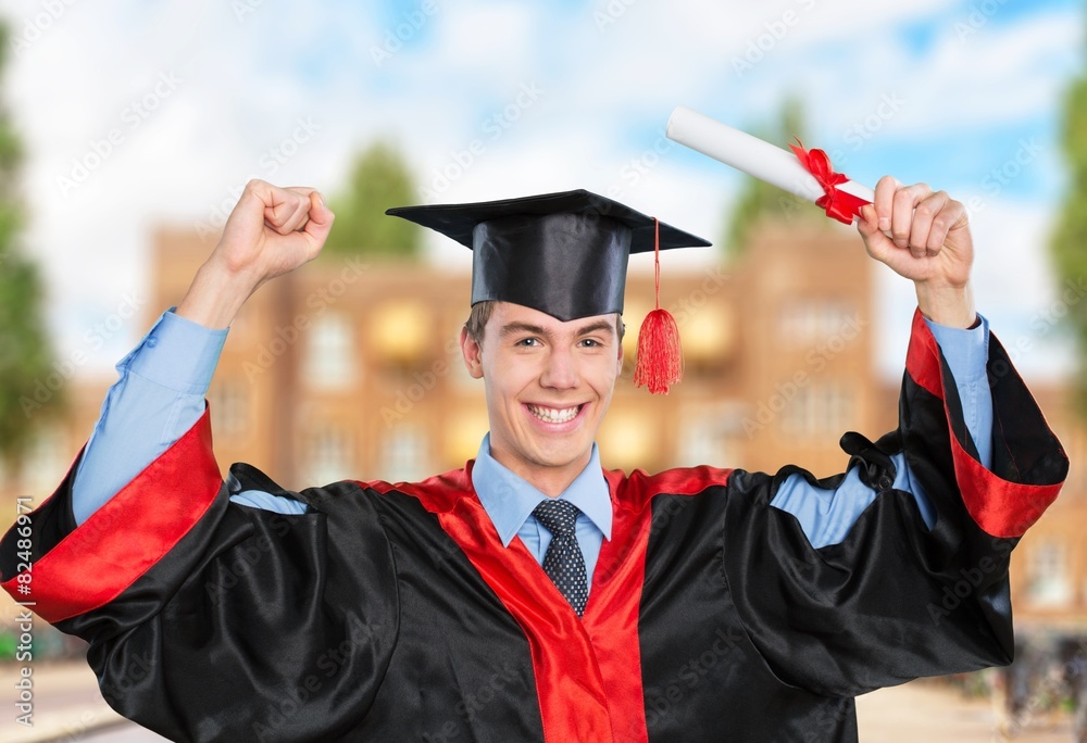 Graduation. Boy in graduation robes holding a diploma