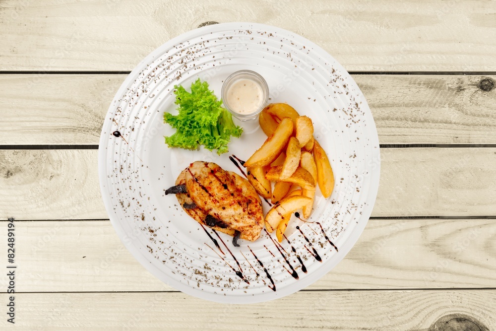 Background. Grilled steak, French fries and vegetables