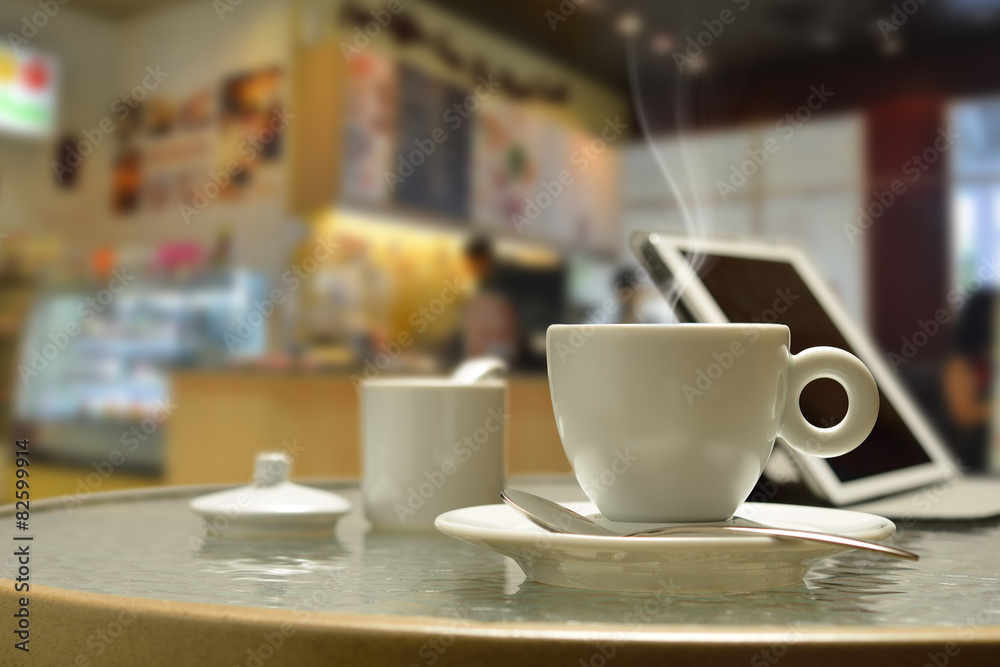 Cup of coffee with smoke and tablet computer in coffee shop