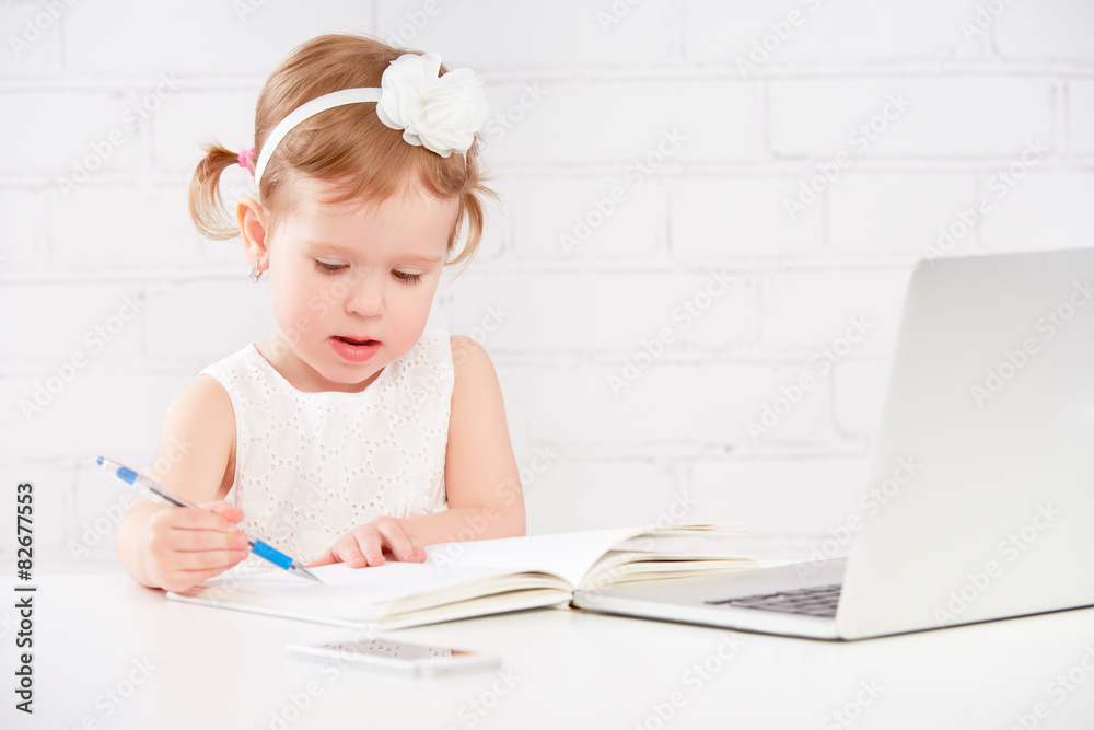 little child baby girl works at computer at home