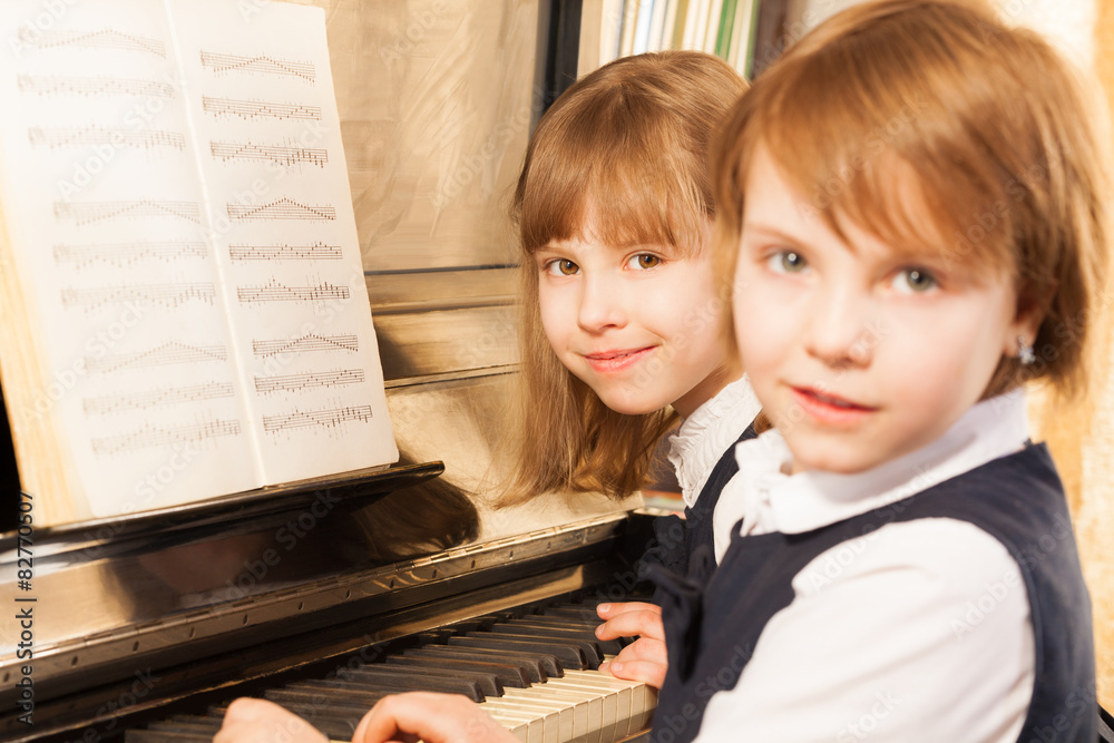 Smiling beautiful small girls playing piano