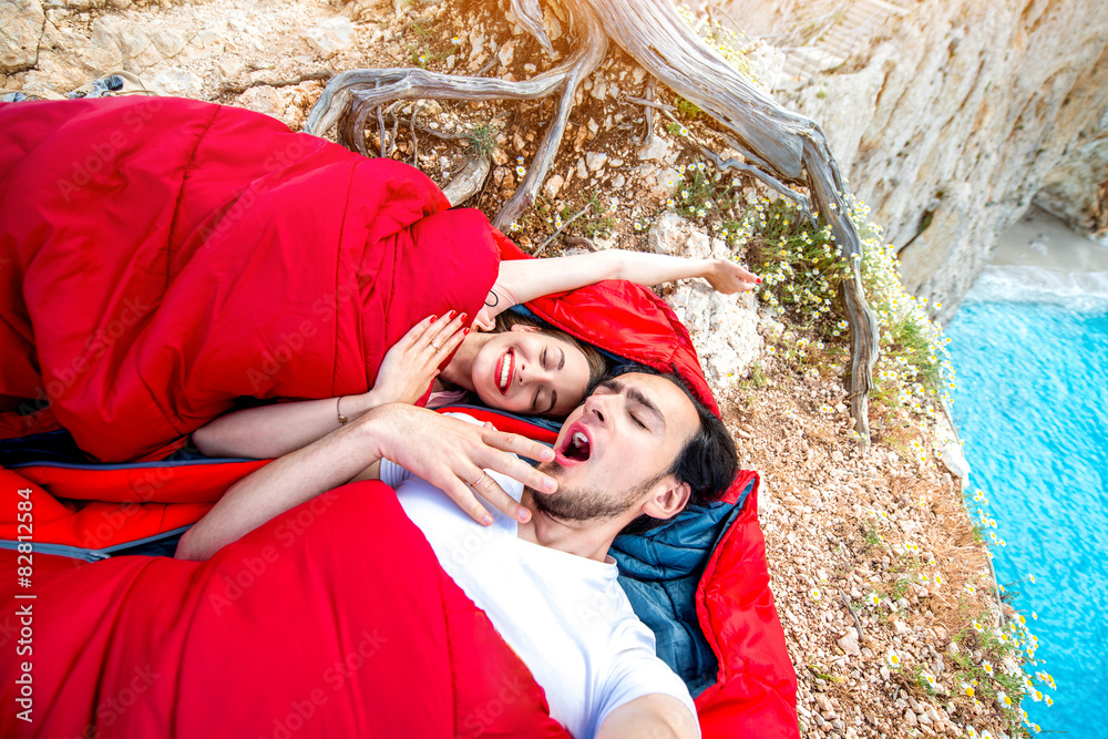 Young couple in sleeping bags near the sea