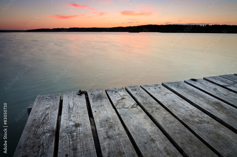 Small wooden pier on big lake at sunset