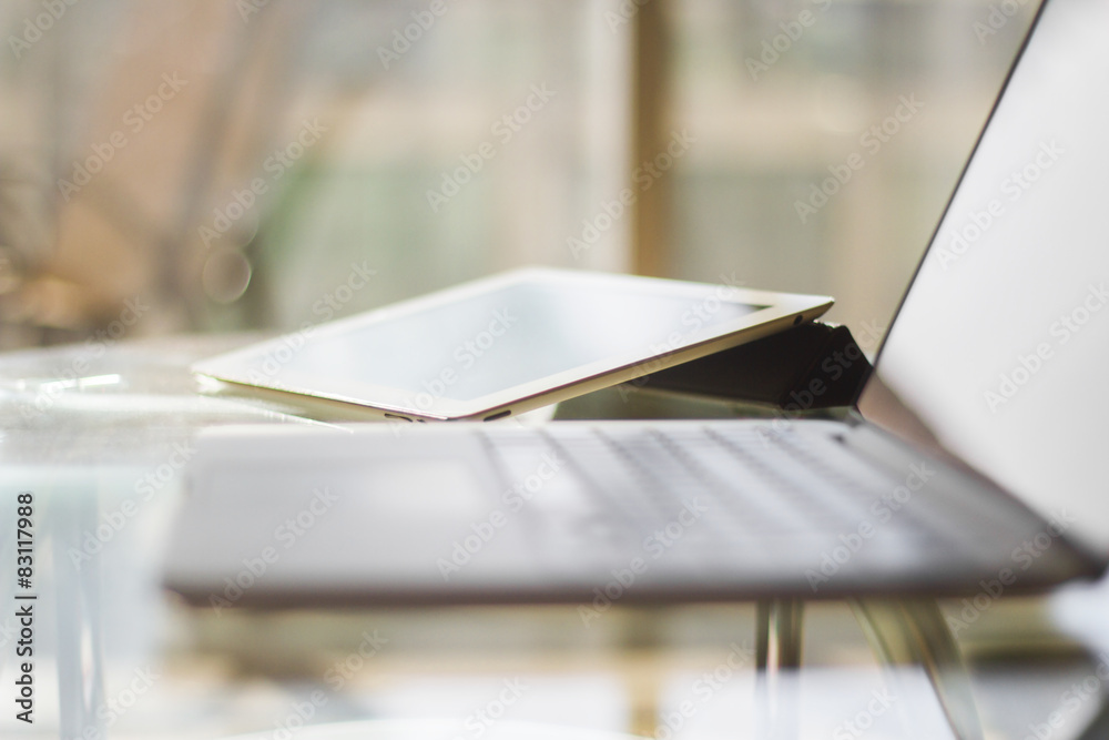 laptop and digital tablet on a glass table, shallow depth of fie