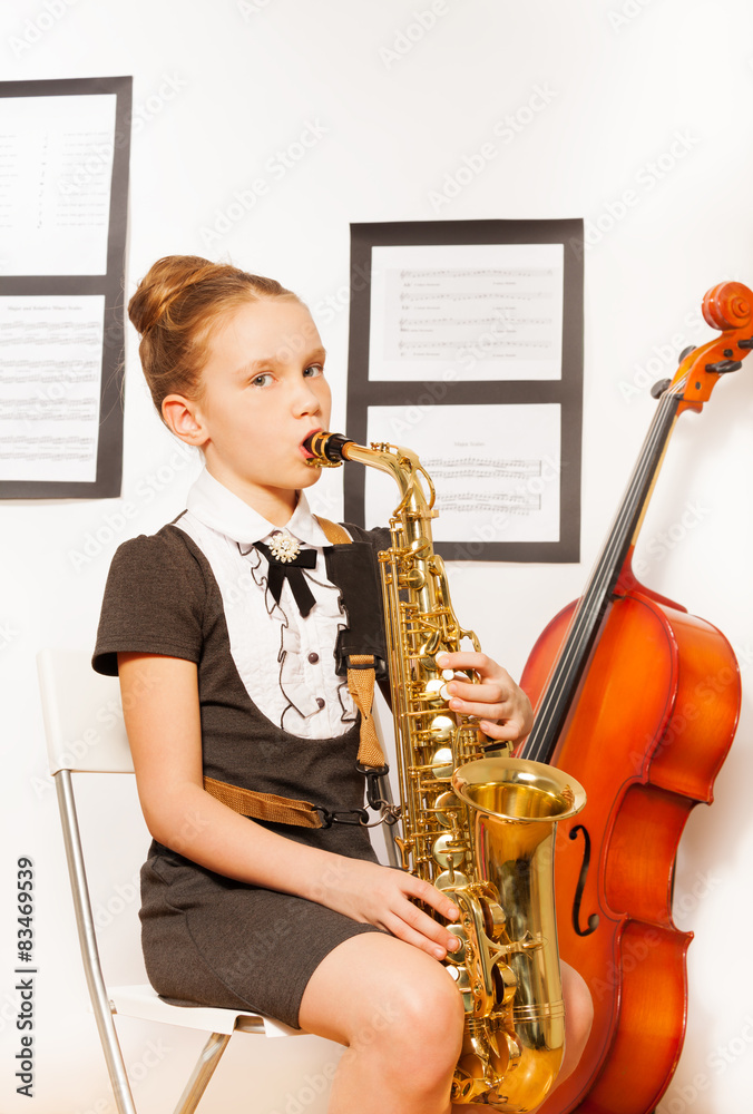 Beautiful girl in dress holding alto saxophone