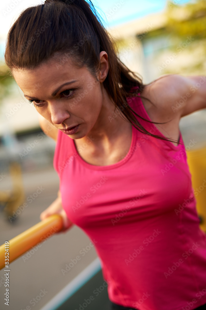 Close up of woman concentrating while doing tricep dips.