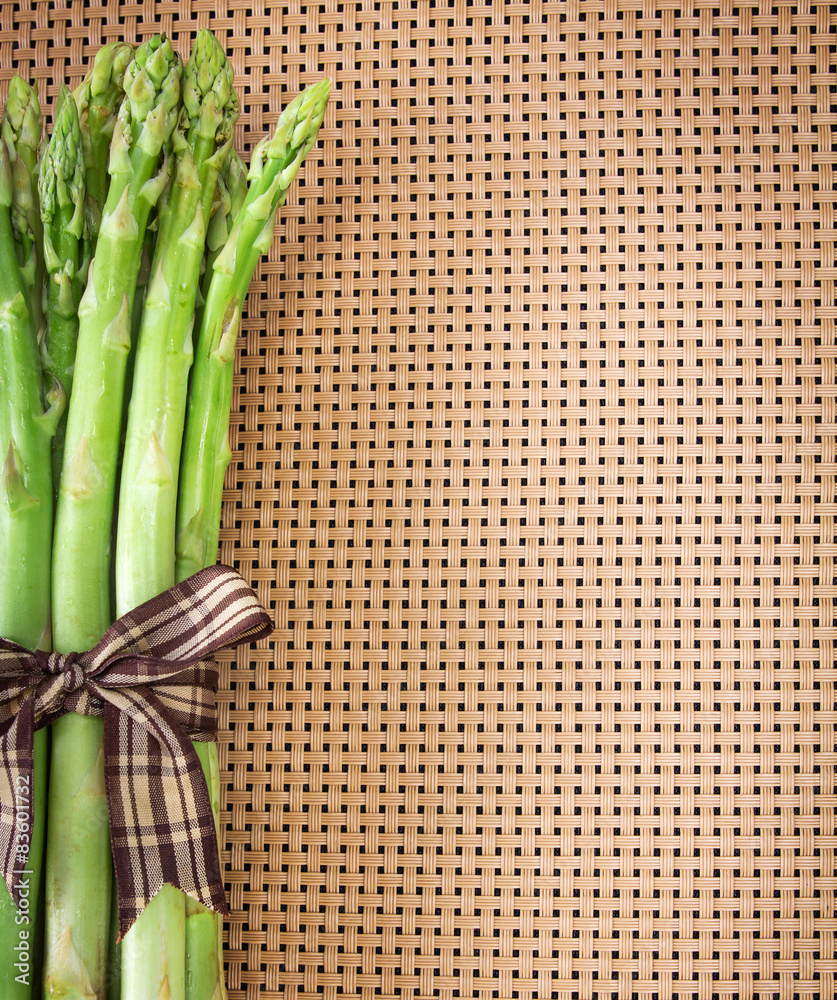 Asparagus bind with brown ribbon on brown wickerwork background