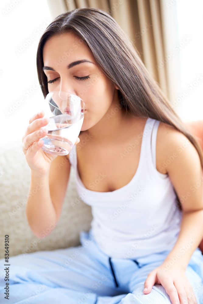 Woman drinking glass of water  leaning forward.