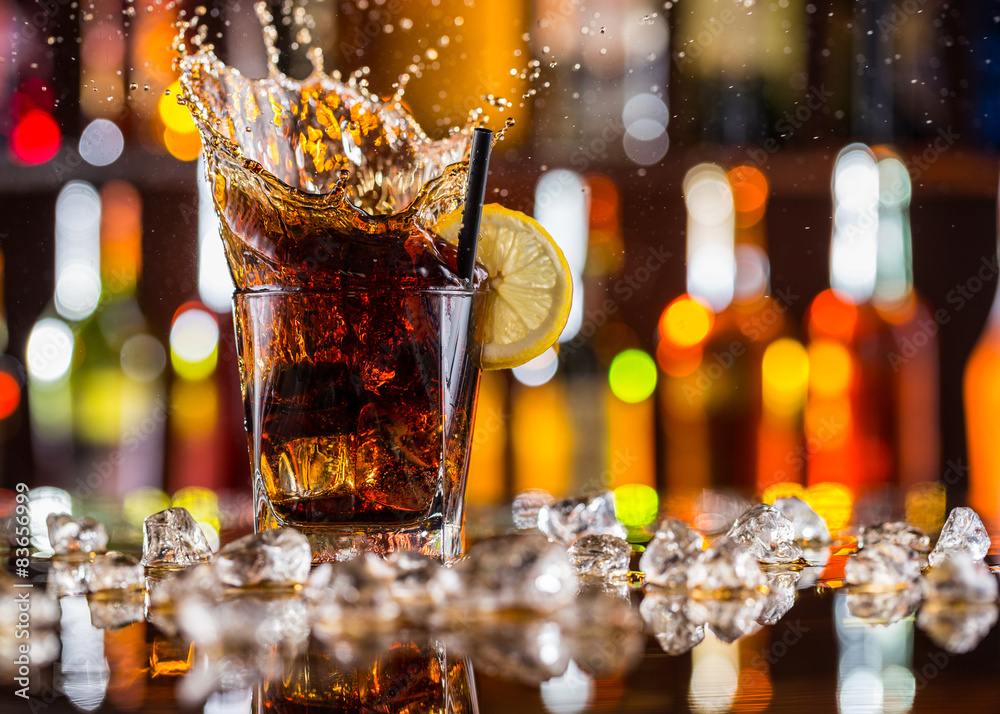 Glass of cola drink with splash on bar counter