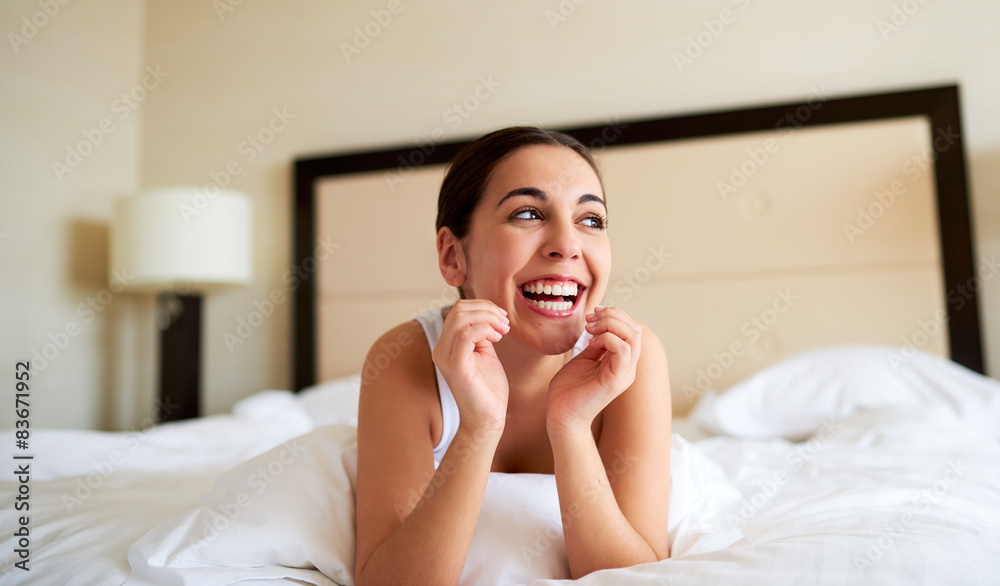 Woman lying down in bed and smiling.