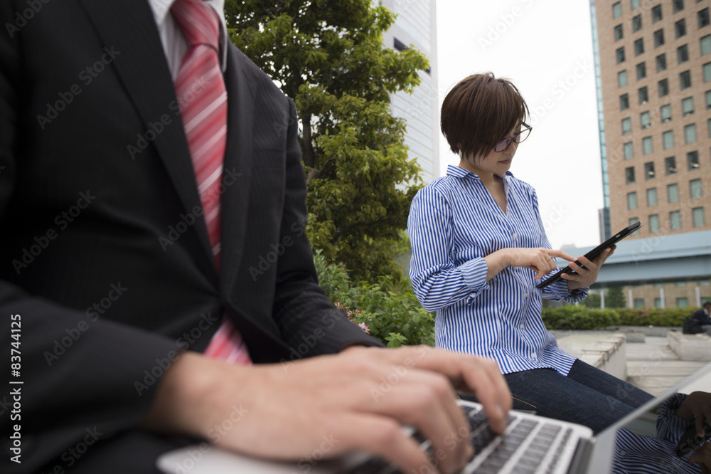 Men are open laptop on a bench in the park