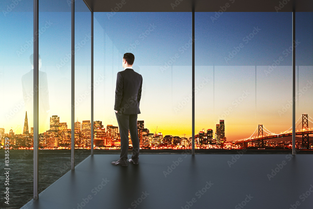 businessman in the office looking over the city at sunset