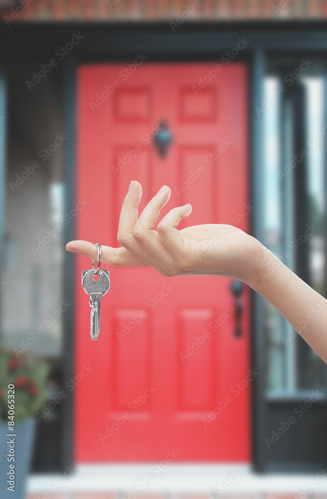 Mano con chiave sfondo porta rossa di casa