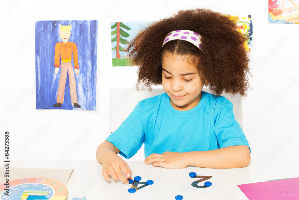 Girl puts blue coins learning to count