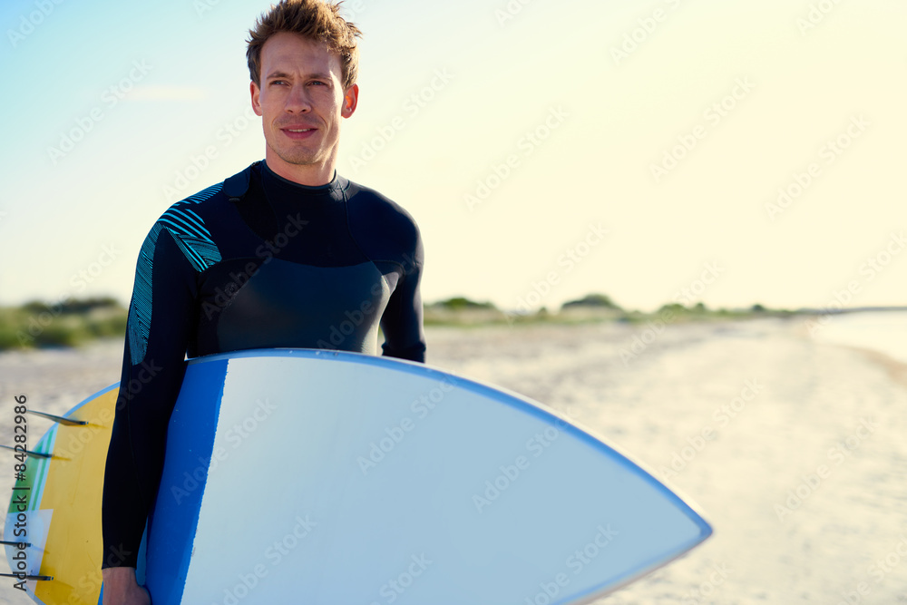 Serious handsome male surfer posing with his board