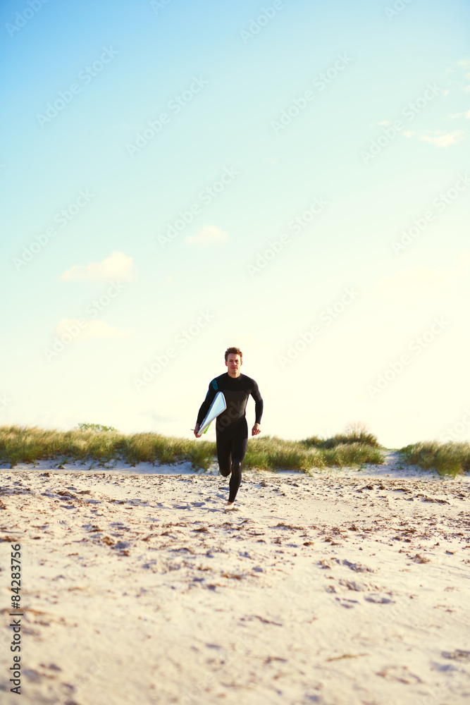 Athletic surfer running towards the surf