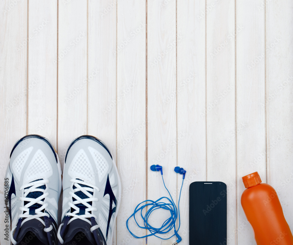 Sport equipment. Sneakers, water, earphones and phone on wooden