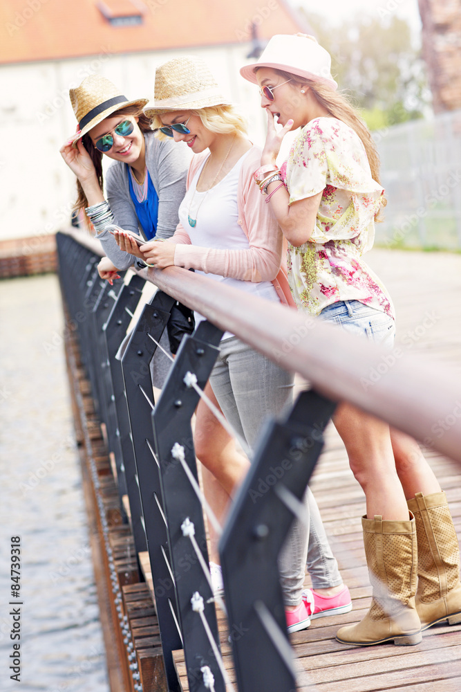 Group of girl friends using smartphone in the city