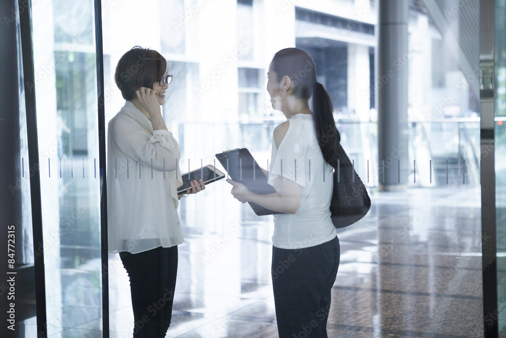 Two women have a chatting in the glass-walled building